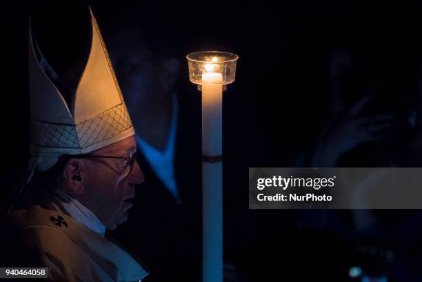 Pope Francis holds a candle as he presides over a solemn Easter vigil ceremony in St. Peter's Basilica at the Vatican, Saturday, March 31, 2018.