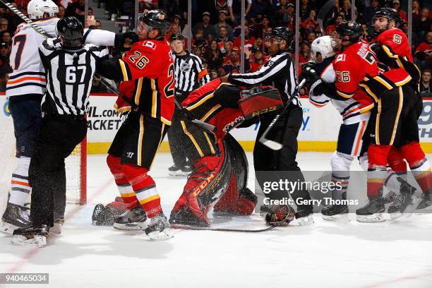 Michael Stone and Mike Smith of the Calgary Flames push and shover after the whistle against Milan Lucic of the Edmonton Oilers during an NHL game on...