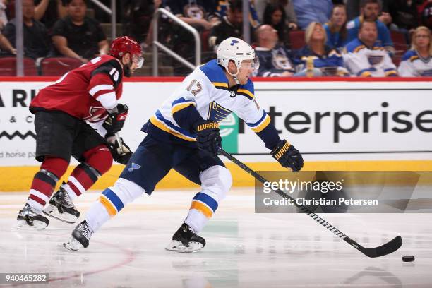 Jaden Schwartz of the St. Louis Blues skates with the puck ahead of Brad Richardson of the Arizona Coyotes during the third period of the NHL game at...