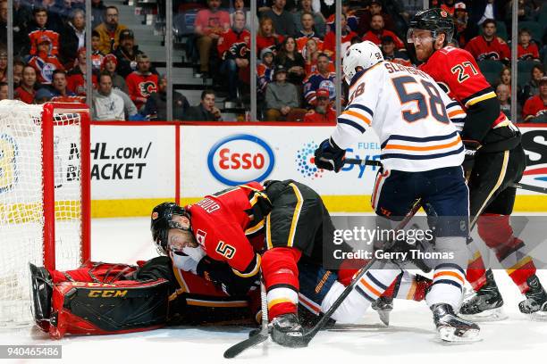 Mark Giordano and Mike Smith of the Calgary Flames cover the puck during an NHL game against the Edmonton Oilers on March 31, 2018 at the Scotiabank...