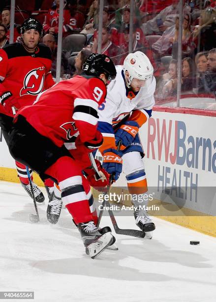 Taylor Hall of the New Jersey Devils and Ryan Pulock of the New York Islanders battle for a loose puck during the game at Prudential Center on March...