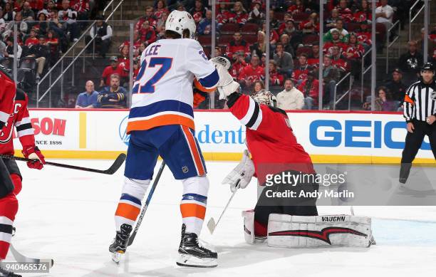 Keith Kinkaid of the New Jersey Devils makes a glove save while being screened by Anders Lee of the New York Islanders during the game at Prudential...