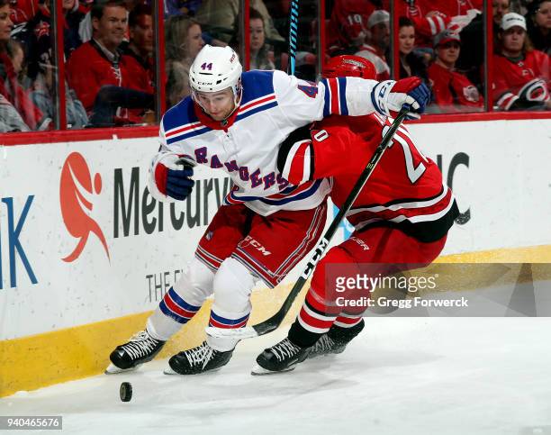 Sebastian Aho of the Carolina Hurricanes knocks Neal Pionk of the New York Rangers off the puck during an NHL game on March 31, 2018 at PNC Arena in...