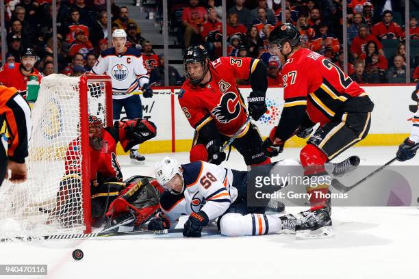Troy Brouwer and Dougie Hamilton of the Calgary Flames clear the rebound against Anton Slepyshev of the Edmonton Oilers during an NHL game on March...