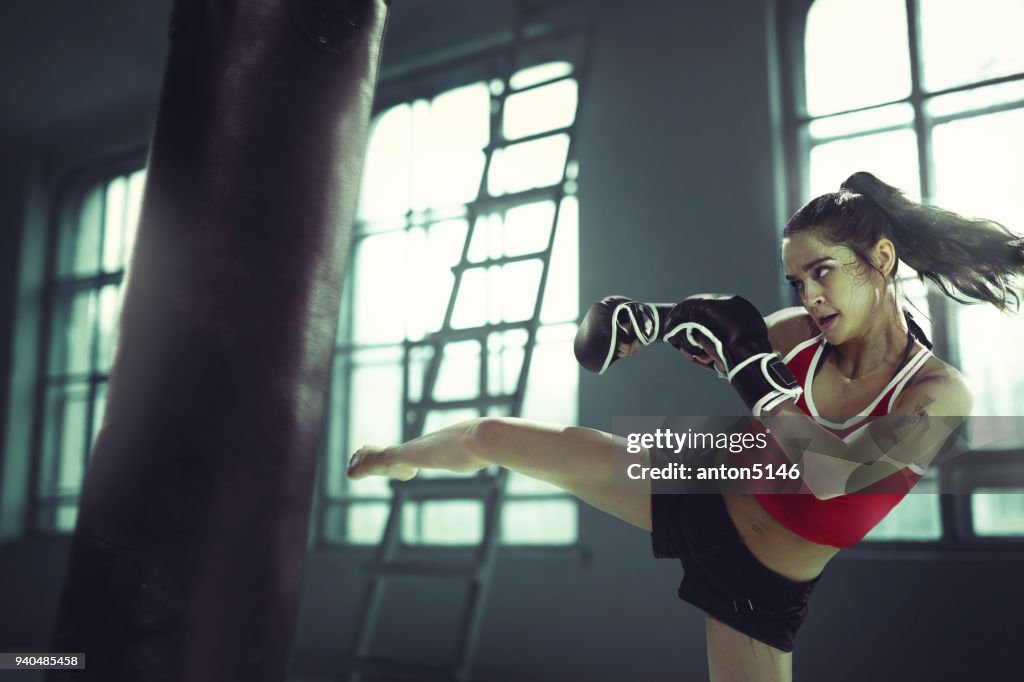 Young woman boxing workout in an old dark gym