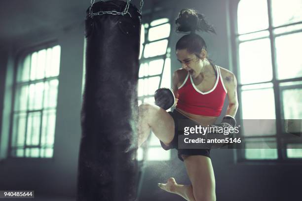 mujer joven de boxeo en un viejo oscuro de ejercicios en el gimnasio - kick boxing fotografías e imágenes de stock