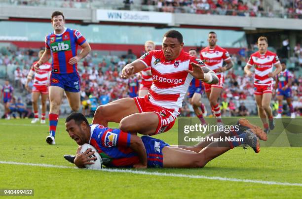 Tauta Moga of the Knights scores as Tyson Frizell of the Dragons attempts to stop him during the round four NRL match between the St George Illawarra...