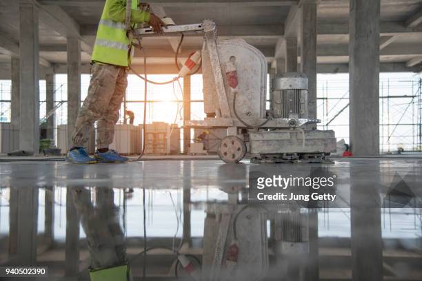 construction worker produces the grout and finish wet concrete with a special tool. float blades. for smoothing and polishing concrete, concrete floors - building damage stockfoto's en -beelden