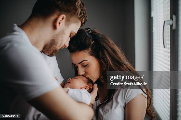 lächelnde junge eltern mit ihrem kleinen mädchen zu hause - mother and daughter kiss happy stock-fotos und bilder