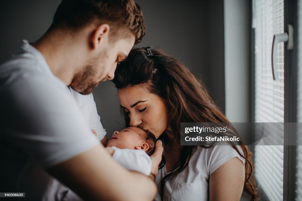 Smiling young parents with their baby girl at home