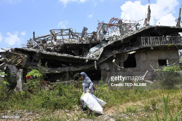 Resident carrying salvaged belongings walks past destroyed buildings during a visit to the main battle area in Marawi City, in southern island of...