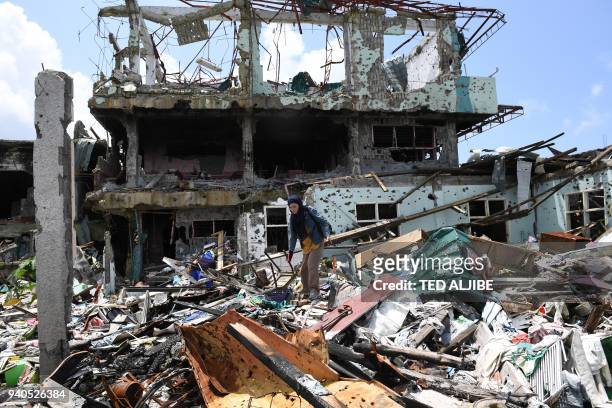 Resident stands amongst the rubbles of her destroyed house, as she tries to salvage belongings during a visit to the main battle area in Marawi City,...