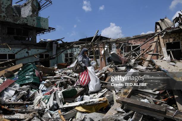 Resident collects salvageable belongings from her destroyed house during a visit to the main battle area in Marawi City, in southern island of...