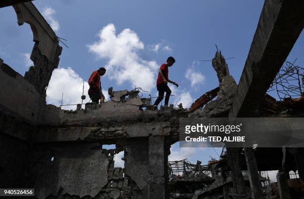 Residents across a concrete beam of their destroyed house as they survey the damage during a visit to the main battle area in Marawi City, in...
