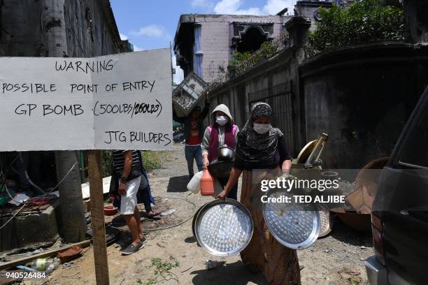 Residents carry belongings collected from their destroyed house during a visit to the main battle area in Marawi City, in southern island of Mindanao...