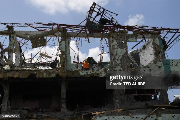 Resident stands on his destroyed house, as he tries to salvage belongings during a visit to the main battle area in Marawi City, in southern island...