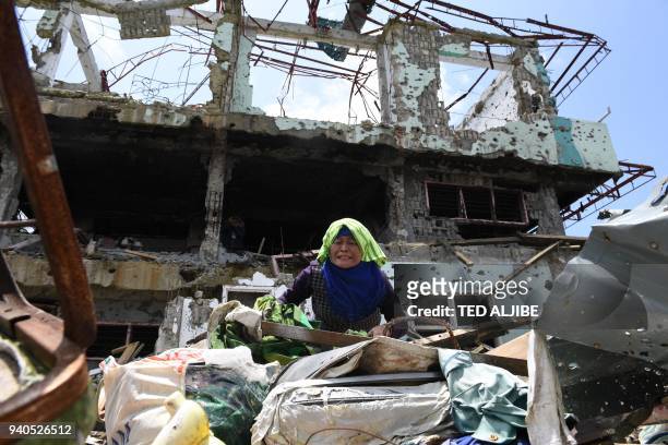 Resident tries to collect salvageable belongings from her destroyed house during a visit to the main battle area in Marawi City, in southern island...
