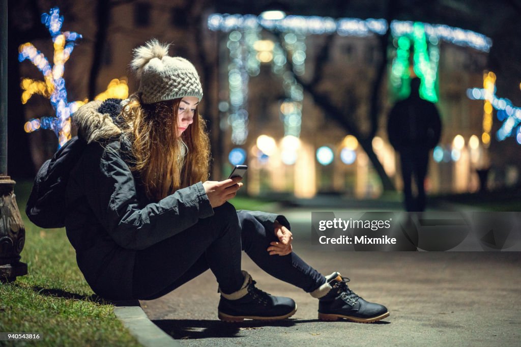 Depressed woman sitting under street lamp