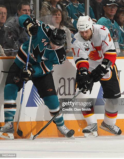 Brian McGrattan of the Calgary Flames digs the puck out from under Marc-Edouard Vlasic of the San Jose Sharks during an NHL game on December 5, 2009...