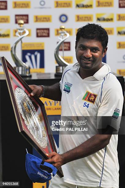 Sri Lankan cricketer Muttiah Muralitharan receives a trophy for his contribution as the Test series' highest wickettaker on the final day of the...