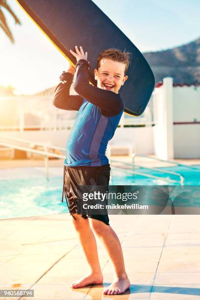 junge spielt mit surfbrett schwimmbecken selbst auf urlaub - mikkelwilliam stock-fotos und bilder