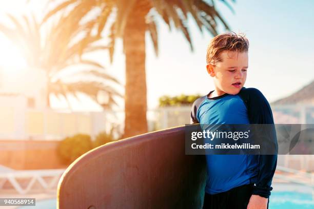 junge hält surfbrett und befasst sich mit schwimmbad - mikkelwilliam stock-fotos und bilder