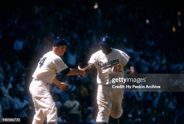 Jackie Robinson of the Brooklyn Dodgers is congratulated by manager Walter Alston after hitting a homerun during an MLB game against the St. Louis...