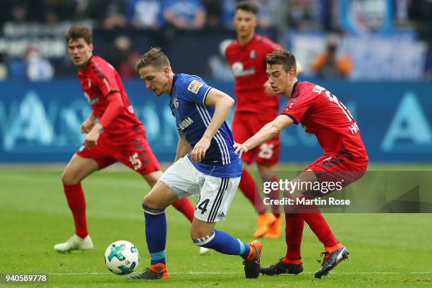 Bastian Oczipka of Schalke is chased by Pascal Stenzel of Freiburg during the Bundesliga match between FC Schalke 04 and Sport-Club Freiburg at...