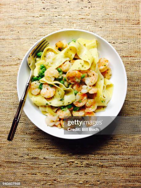 shrimp pappardelle pasta meal in a white bowl with fork, on a rough woven straw place mat - dragon stockfoto's en -beelden