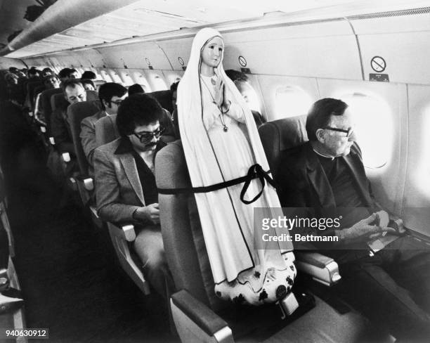 Father Patrick Moore, of the Scarborough Foreign Mission, sits next to the World Pilgrim Statue of our Lady of Fatima en route to the Port of Spain,...