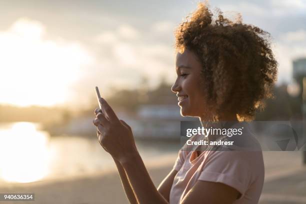 lässige frau sms auf ihrem handy am strand - smartphone strand stock-fotos und bilder