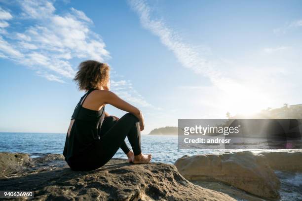 peaceful woman at the beach watching the sunrise - sunrise yoga stock pictures, royalty-free photos & images
