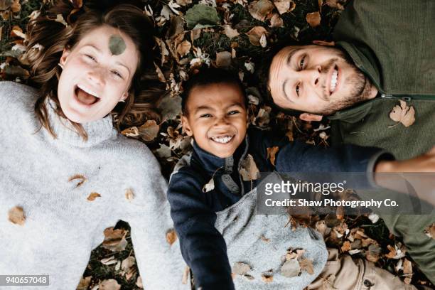 Multi racial family photos with adoptive son in fall leaves