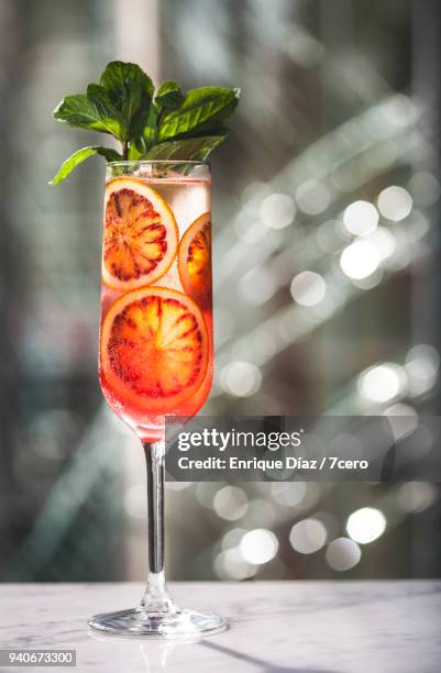 blood orange cava cocktail with mint and broken glass - bloedsinaasappel stockfoto's en -beelden