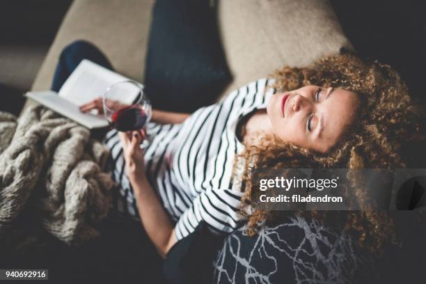 relaxed young woman reading a book - drinking alcohol at home stock pictures, royalty-free photos & images