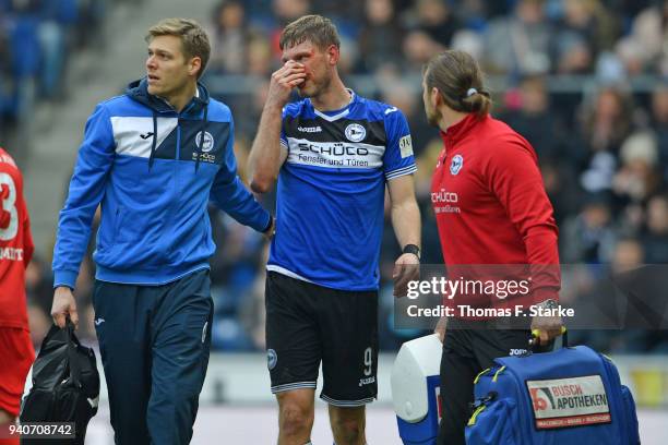 Fabian Klos of Bielefeld receives medical treatment by physiotherapist Michael Schweika and doctor Stefan Budde during the Second Bundesliga match...