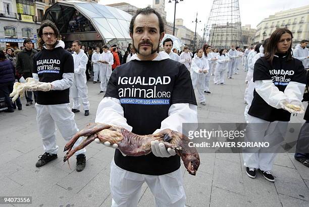 An activist of the 'IgualdadAnimal' organization holds a skinless dead bison during a demonstration for the abolition of animal slavery at the Puerta...