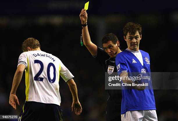 Referee Andre Marriner shows a yellow card to Michael Dawson of Tottenham Hotspur during the Barclays Premier League match between Everton and...