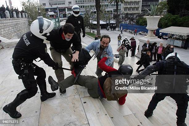 Riot police detain a protestor during a demonstration commemorating the fatal shooting of 15-year-old Alexandros Grigoropoulos' by police a year ago,...