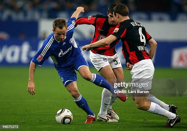 Ivan Rakitic of Schalke is challenged by Nemanja Pejcinovic and Steve von Bergen of Berlin during the Bundesliga match between FC Schalke 04 and...