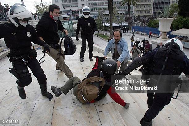 Riot police detain a protestor during a demonstration commemorating the fatal shooting of 15-year-old Alexandros Grigoropoulos' by police a year ago,...