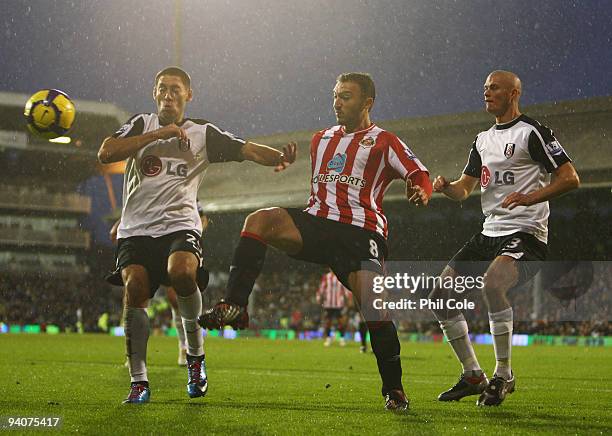 Steed Malbranque of Sunderland is tracked by Clint Dempsey and Paul Konchesky of Fulham during the Barclays Premier League match between Fulham and...