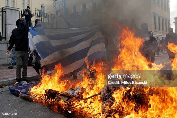 Protestors burn a Greek flag during a demonstration commemorating the fatal shooting of 15-year-old Alexandros Grigoropoulos by police a year ago, on...