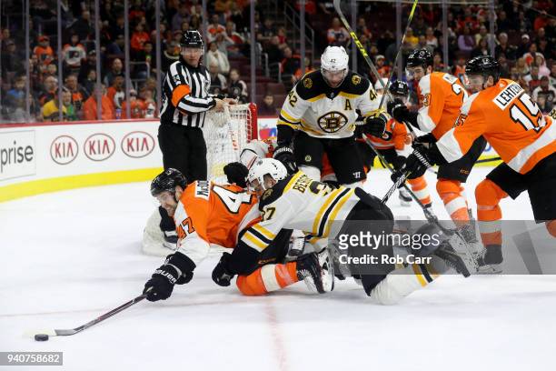 Andrew MacDonald of the Philadelphia Flyers and Patrice Bergeron of the Boston Bruins go after the puck in the third period at Wells Fargo Center on...