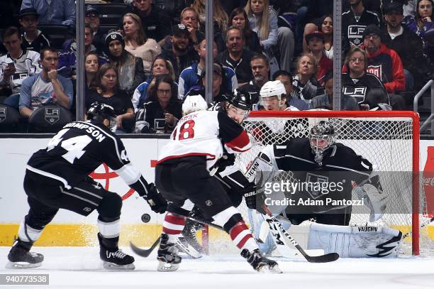 Christian Dvorak of the Arizona Coyotes battles for the puck against Jack Campbell, Drew Doughty, and Nate Thompson of the Los Angeles Kings during...