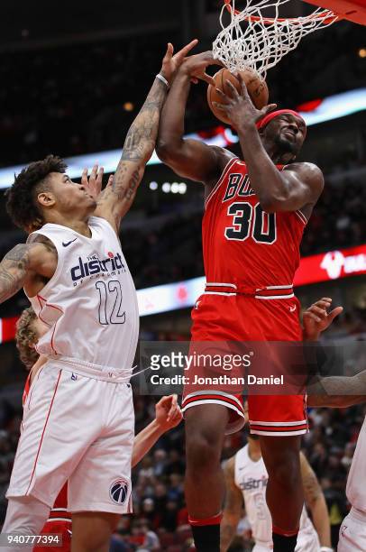 Noah Vonleh of the Chicago Bulls rebounds over Kelly Oubre Jr. #12 of the Washington Wizards at the United Center on April 1, 2018 in Chicago,...