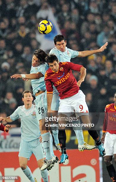 Roma's Montenegrin forward Mirko Vucinic jumps for the ball with Lazio's defender Lorenzo De Silvestri and Lazio's Swiss defender Stephan...