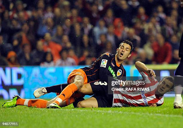 Athletic Bilbao's Koikili Lertxundi and Valencia's David Villa fall on the field during a Spanish league football match, on December 6 at San Mames...