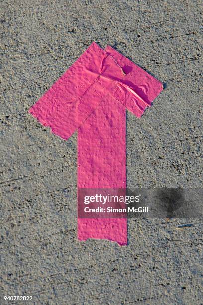 arrow made from pink duct tape on a concrete footpath - provisorisch stockfoto's en -beelden