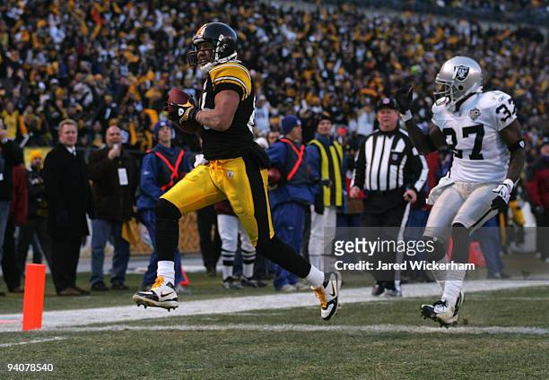 Hines Ward of the Pittsburgh Steelers catches a touchdown pass in the fourth quarter in front of Chris Johnson of the Oakland Raiders during the game...